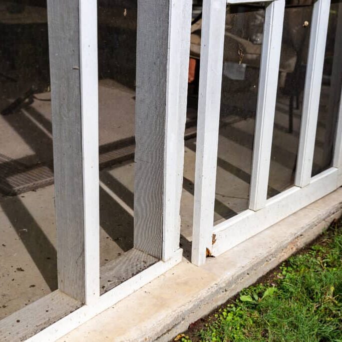 Wooden screen door on back porch with rotten wood